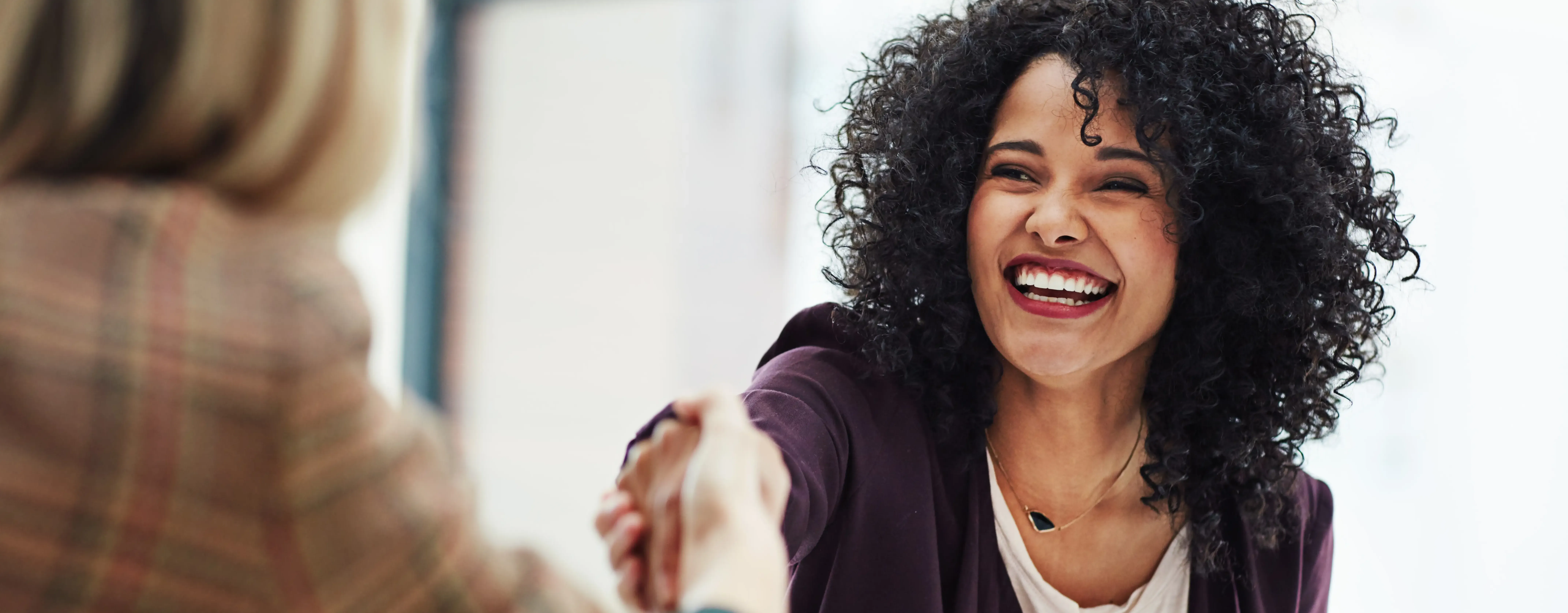 two women shaking hands smiling