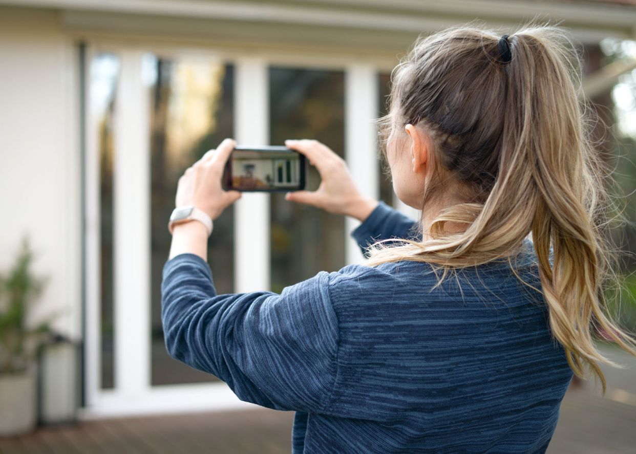 lady taking picture of property damage to upload into insurance cloud solution
